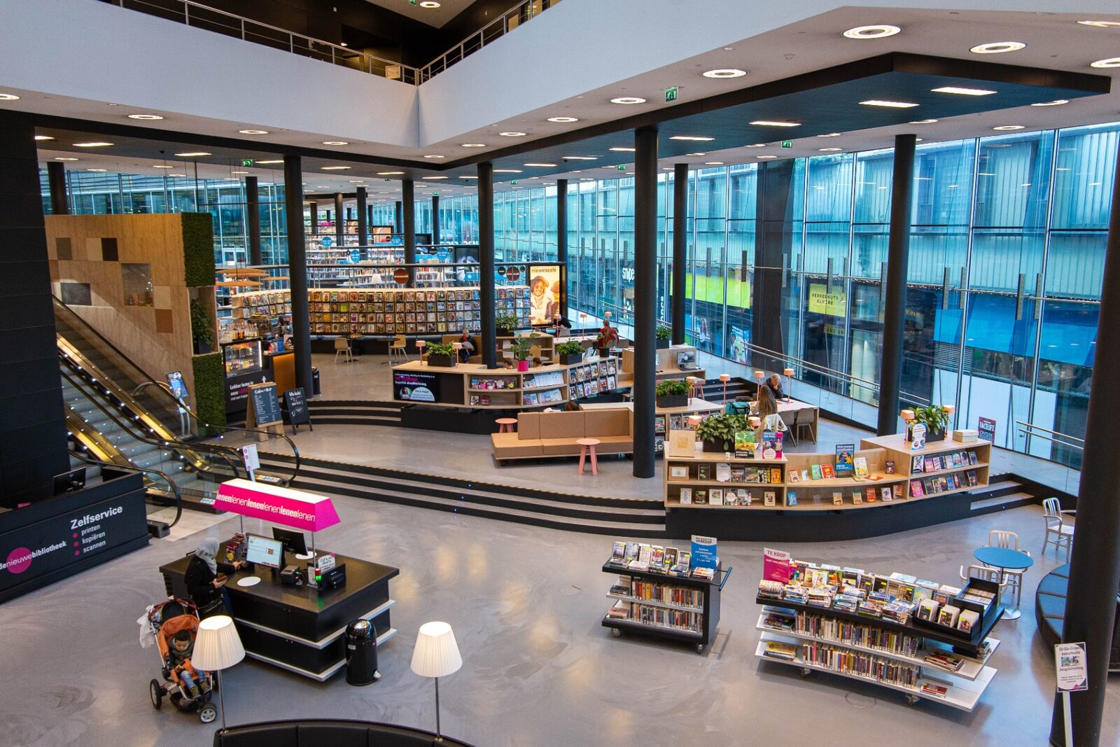 Bibliotheekinterieur met ronde balie en maatwerk kasten in warm hout