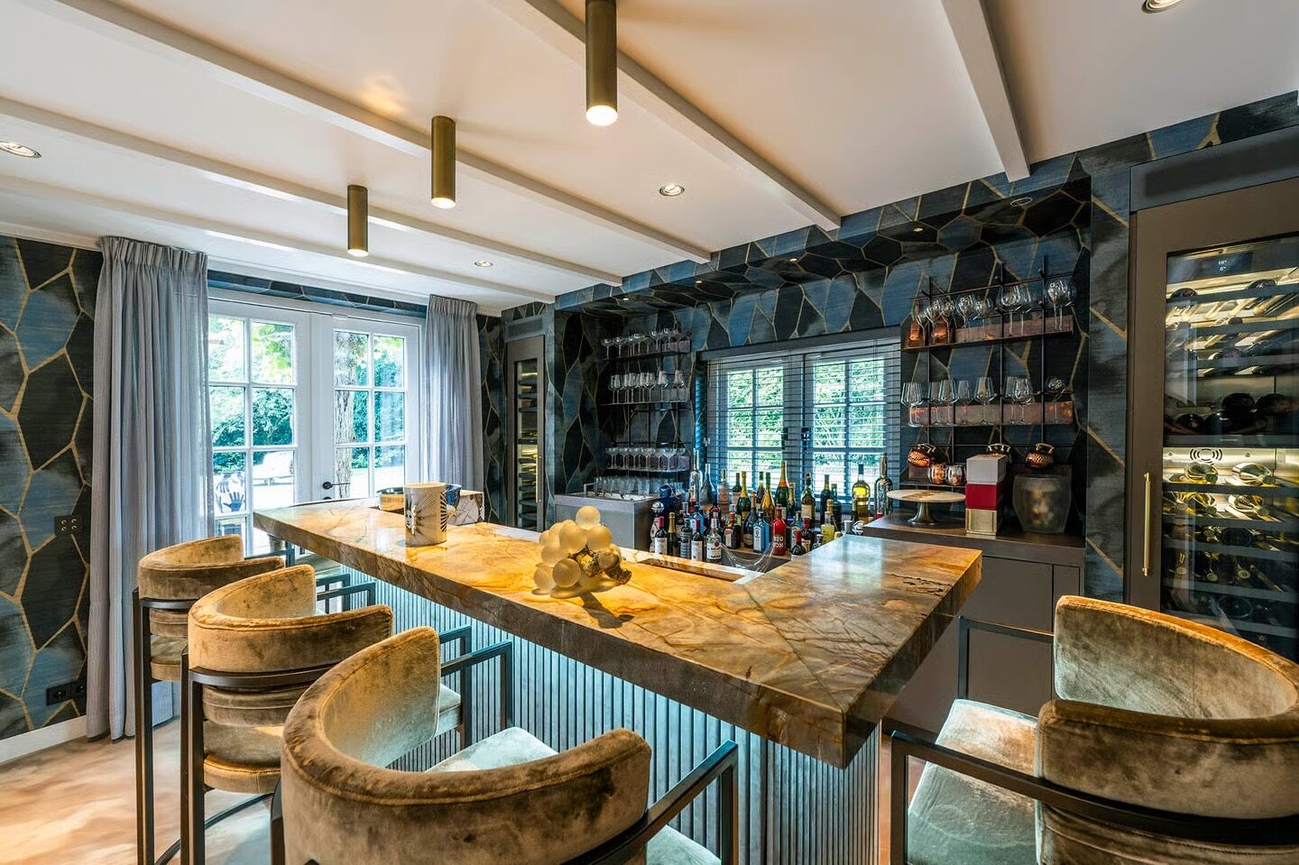 Maatwerk bar met natuurstenen blad, wijnkoeling en barkrukken in een woning